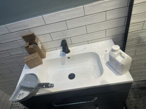 Bathroom sink covered in construction dust and debris before post-construction clean