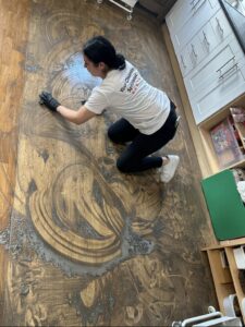 Cleaning specialist scrubbing dirty wooden floor by hand during deep clean service