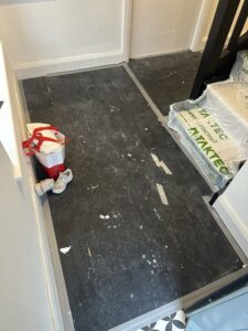 Commercial floor scrubbing machine cleaning a blue vinyl floor in a large room