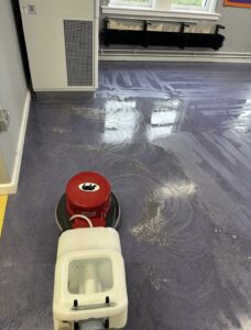 Cleaning operative deep cleaning a healthcare corridor with ladders and cleaning equipment