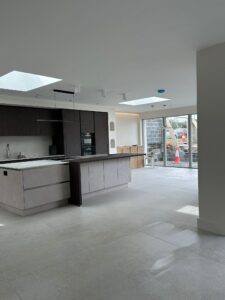 Wide angle view of open plan new build kitchen with island and bi-fold doors after renovation clean