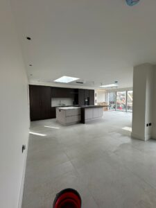 Wide angle view of open plan new build kitchen and living area with island and bi-fold doors after renovation clean