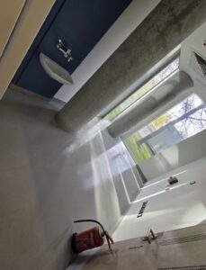 Newly cleaned commercial bathroom with exposed concrete beams and sparkling white surfaces after post-construction sparkle clean