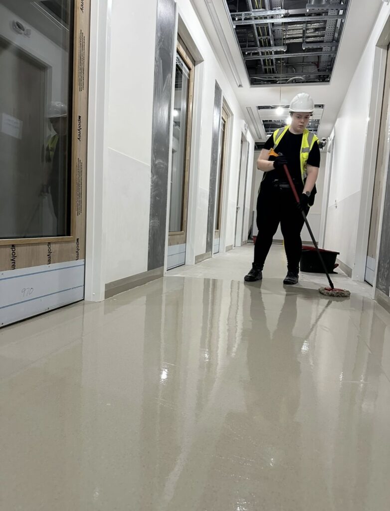 Female construction cleaning operative mopping shiny corridor floor in new-build Ireland