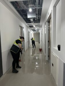 Two cleaning operatives in hi-vis vests mopping a commercial corridor during post-construction clean Ireland