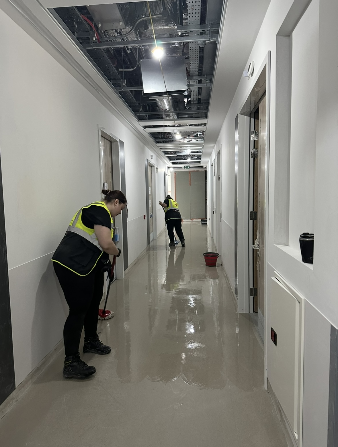 Two cleaning operatives in hi-vis vests mopping a commercial corridor during post-construction clean Ireland