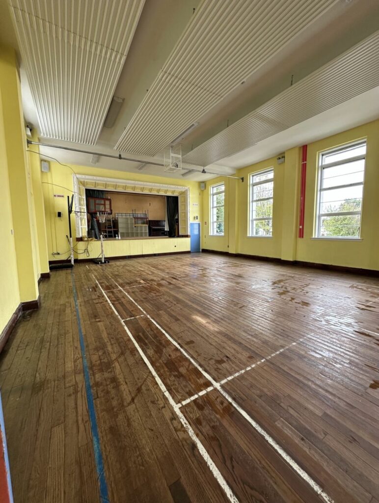 School assembly hall with dirty hardwood floor before post-construction cleaning Ireland