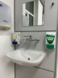 Spotlessly clean clinical hand wash sink with soap dispensers mirror and paper towel holder after post-construction deep clean