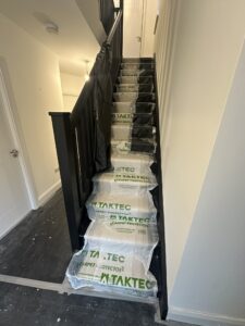 Residential staircase fully covered with Taktec carpet protector film during renovation cleaning process