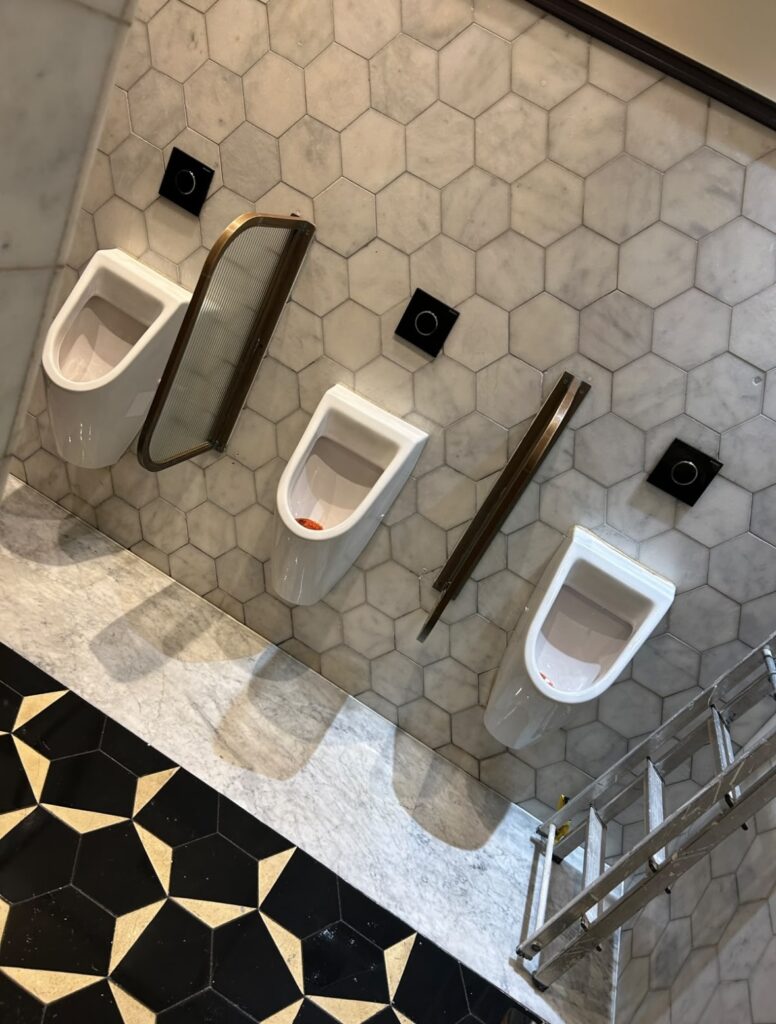Hexaclean Solutions restaurant fit out cleaning Dublin — luxury mens bathroom with marble tiles and brass fittings cleaned to handover standard