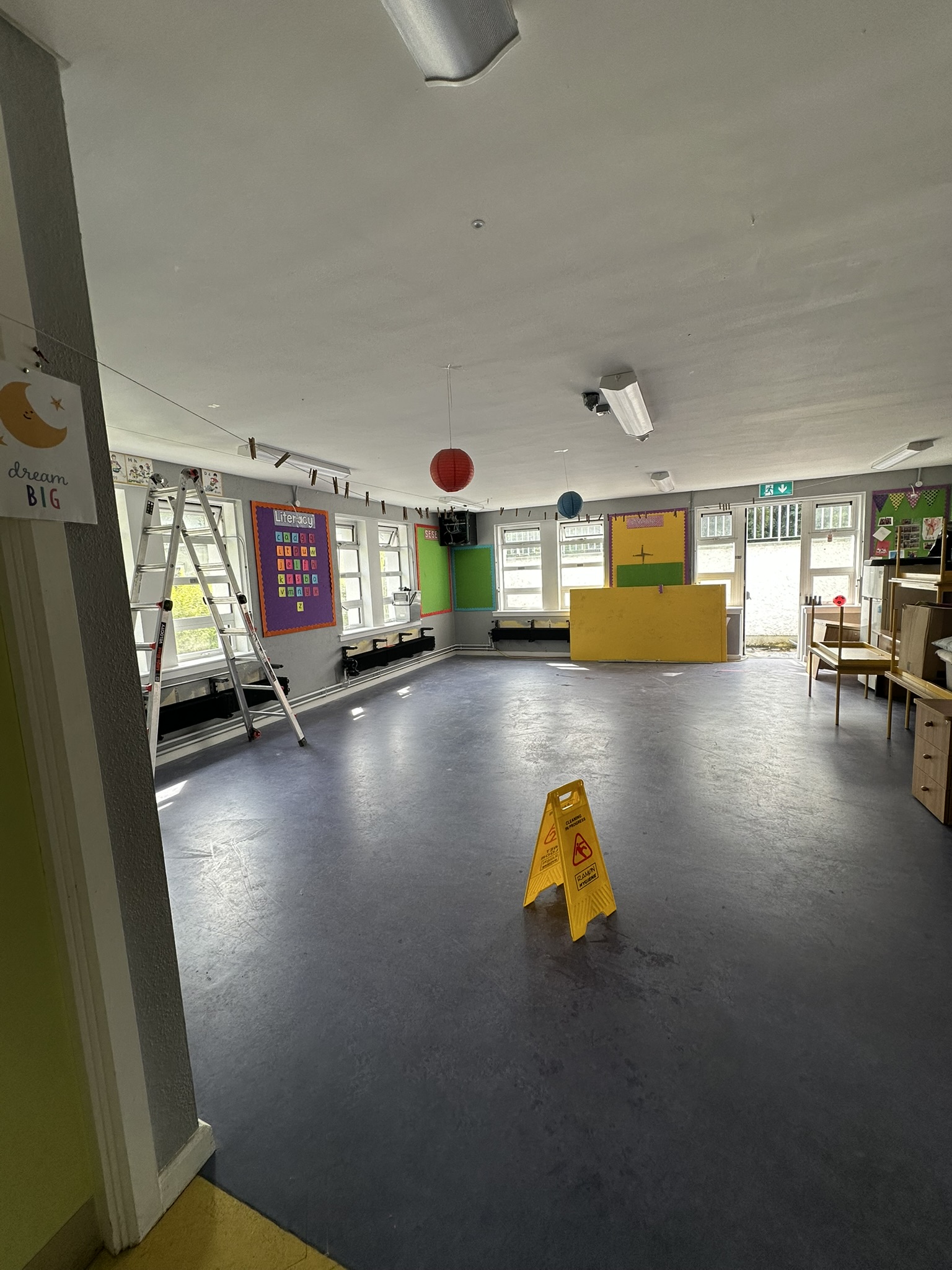 Buffed school floor with wet floor caution sign during cleaning