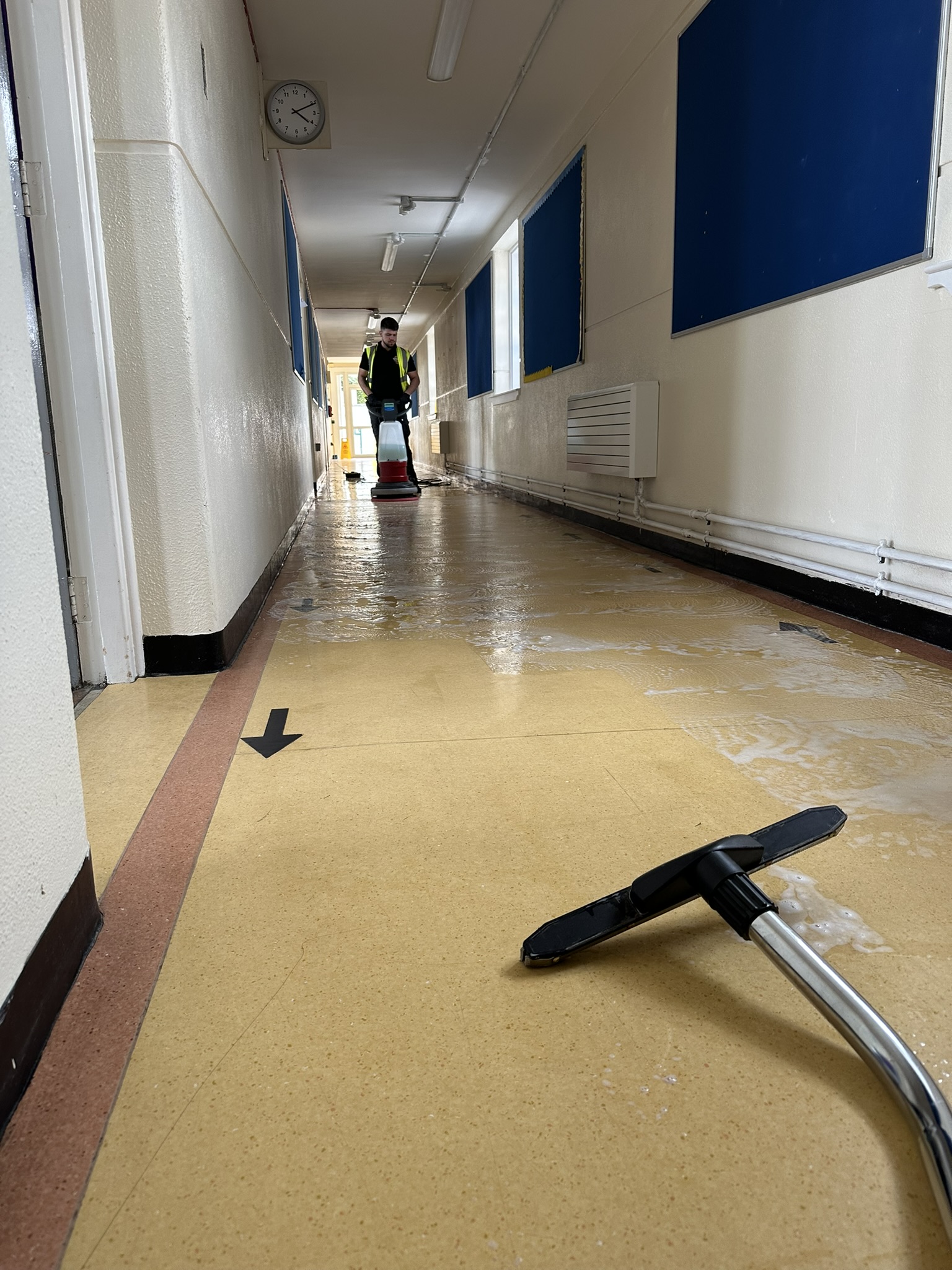 Wet vacuuming shining corridor floor after buffing in school