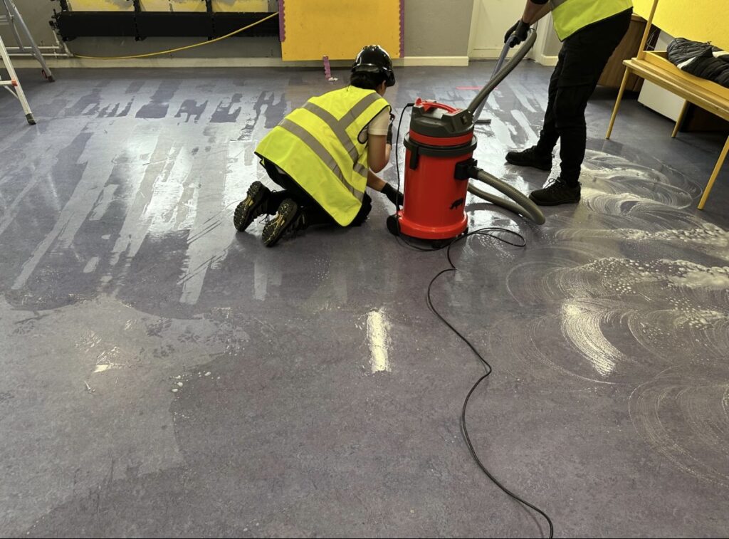 Two Hexaclean Solutions employees buffing linoleum floor after construction