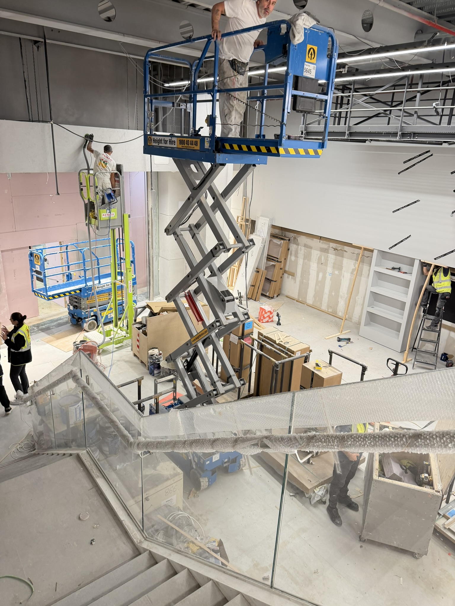 Active commercial retail fit-out in Dundrum, Dublin with MEWPs and multiple trades working before post-construction cleaning and final handover.