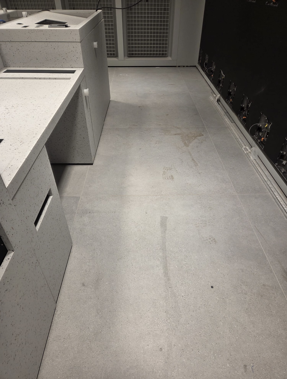 Retail fit-out floor in Dundrum, Dublin before post-construction cleaning, showing construction dust, footprints and residue on newly installed tiles.