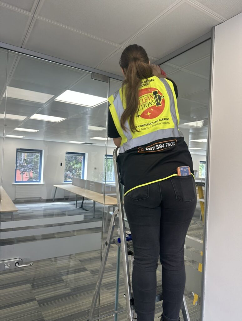Hexaclean cleaner carrying out glass cleaning during an office fit out after builders clean in Dublin.