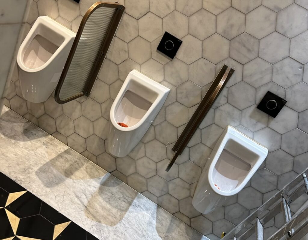 Hexaclean Solutions restaurant fit out cleaning Dublin — luxury mens bathroom with marble tiles and brass fittings cleaned to handover standard